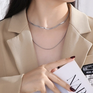 Detail of layered silver stainless steel snake chain necklace on model's neck