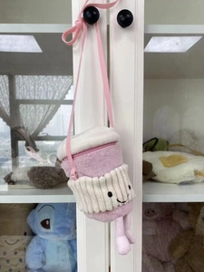 Detail of pink plush crossbody bag in cup shape with cute embroidery and dangling legs