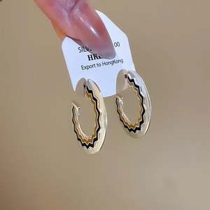 Dettaglio macro di orecchini a cerchio in argento con smalto a zigzag nero giallo bianco