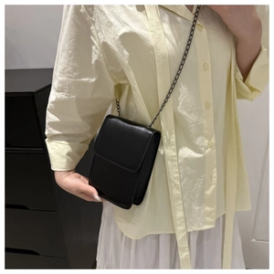 Minimalist black matte leather phone bag with gunmetal chain strap shown on model