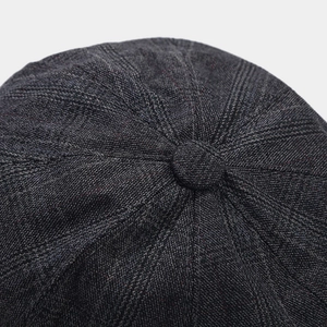 Vista de detalle de la corona de tweed gris oscuro y el botón de una gorra retro