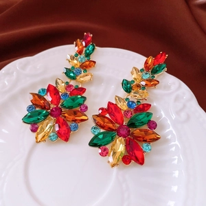 Detailed view of vintage flower earrings with colorful rhinestones on a white ceramic tray