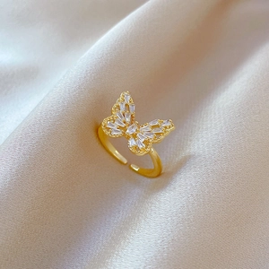 Macro detail of gold butterfly ring with white micro-pave stones on silk background
