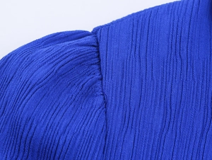 Makroaufnahme des Kleinblauen Stufenkleides zeigt detaillierte plissierte Stoffstruktur
