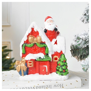 Macro detail of a bright red ceramic Christmas house with snowy roof and golden bow decor