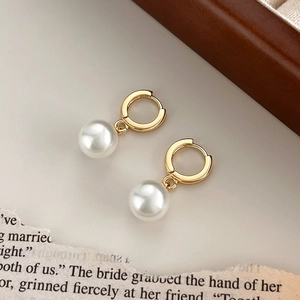 French vintage 18K gold-plated titanium pearl drop earrings on a rustic wooden stand
