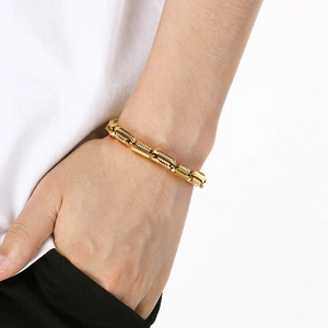 Detail of golden chain bracelet with embossed motorcycle texture on person's wrist