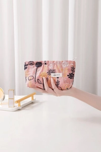 Detail of floral embroidery and zipper closure on a pink fabric cosmetic bag