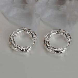 Detailed view of silver hoop earrings with unique lava texture and clasp closure
