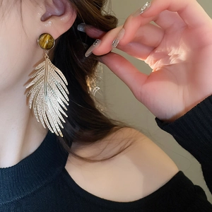 Close-up of vintage gold leaf earrings with tiger eye stone on model for an elegant look