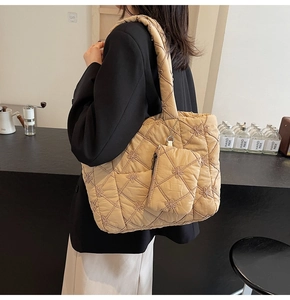 Close-up of beige quilted tote bag with floral embroidery and matching small pouch