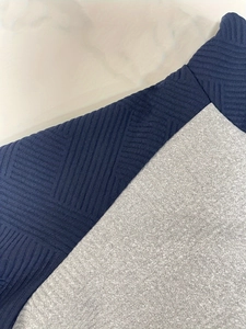 Gros plan sur le tricot texturé bleu foncé et le tissu gris lisse du sweat à manches longues