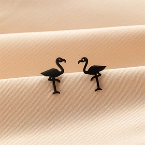 Macro shot of black flamingo stud earrings on elegant champagne satin fabric