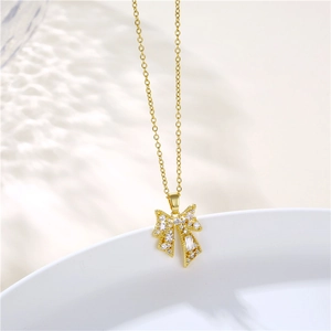 Detail of gold bow necklace with white cubic zirconia stones on white ceramic dish
