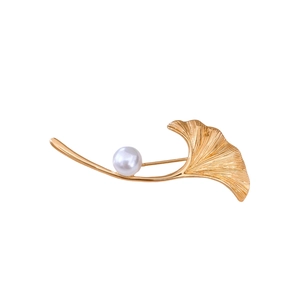 Eleganter 18K vergoldeter Ginkgoblatt-Anstecker mit weißer Perle auf weißem Hintergrund
