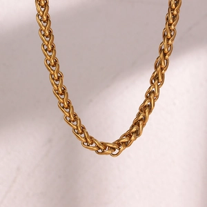 Detail shot of the intricate woven gold wheat chain necklace with 6mm link thickness
