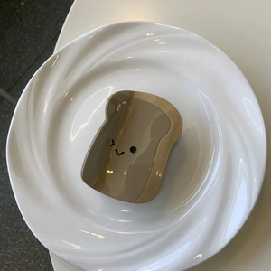 Dettaglio molletta per capelli in acetato a forma di toast con smiley su un piatto