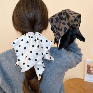 Dettaglio di nastri per capelli in raso di seta con pois e motivi leopardati sulla coda