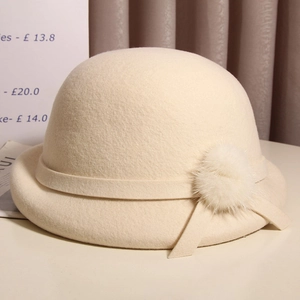Detail of cream wool cloche hat with fluffy fur pom-pom and elegant ribbon trim