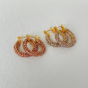 Detail view of gold hoop earrings with pavé set pink and purple zircon crystals