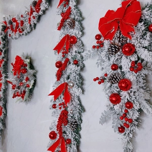 Detail of flocked Christmas wreath and garland with red berries and pine cones