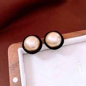 Macro detail of round velvet-wrapped pearl earrings on a premium wooden jewelry box