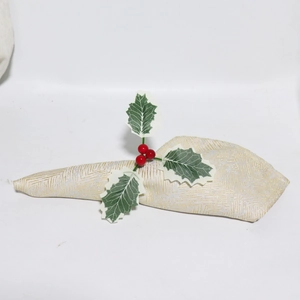 Detail von Weihnachts-Serviettenring mit roten Beeren und grünen Blättern auf Goldstoff