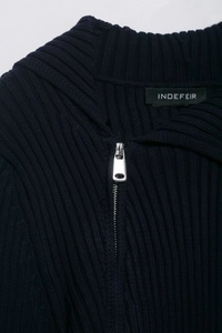 Detail of navy blue ribbed knit texture and polished silver metal zipper on the sweater