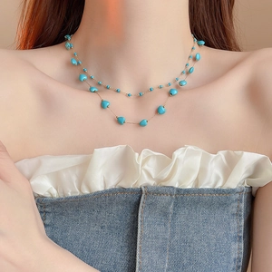 Detail of bohemian gold plated layered necklace with turquoise beads and heart charms