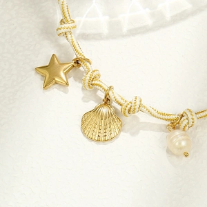 Detail of woven bracelet with gold starfish, scallop shell charms and a white pearl