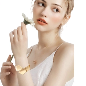 Detail of wide asymmetrical double-layer gold bangle with pearls on model's wrist