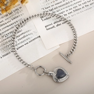Détail d'un bracelet en argent avec cœur en opale et fermoir OT sur des pages de livre