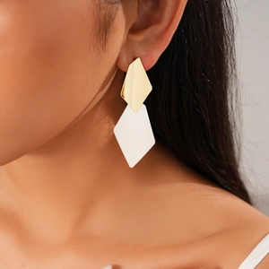 Detail of minimalist geometric double rhombus earrings in gold and white on model