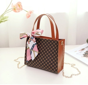 Detailed shot of brown monogram handbag with pink silk scarf and golden chain strap