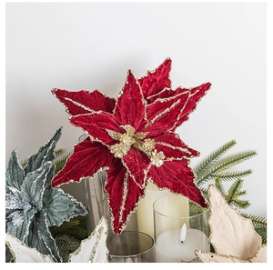 Close-up of velvet poinsettia flowers with red petals and gold glitter on pine branch