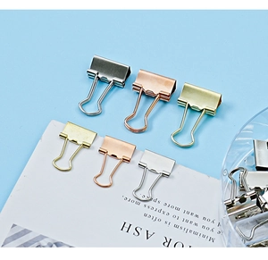 Macro shot of silver, gold, and rose gold binder clips in a minimalist office setting