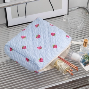 Vue détaillée de la trousse de maquillage matelassée à rayures bleues et fraises