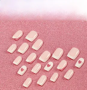 Pink French tips press-on nails with red hearts and glitter on sandy texture