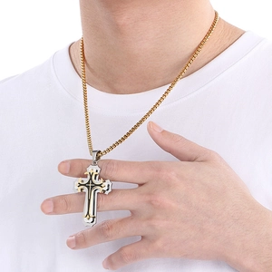 Detail of male model wearing multi-layered gold and silver steel cross pendant necklace