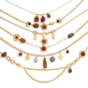 Bohemian gold layered necklace set with resin charms, pearls, and coins on white background