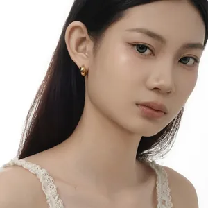 Close-up of a model wearing high-polish gold C-shape hoop earrings in sterling silver
