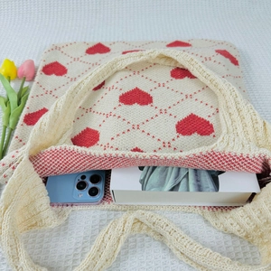 Detail view of the cream knitted tote bag capacity showing a smartphone and book inside