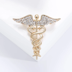 Golden Caduceus brooch with winged snake staff and diamond accents on white background