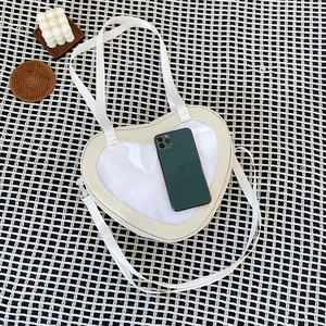 Cream white heart-shaped ita bag with clear window showing phone storage space