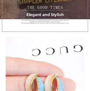 Close-up of French vintage enamel earrings in blue and beige with gold accents