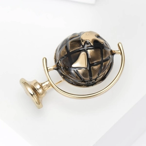 Detailed macro view of golden globe brooch with black enamel continents and latitude lines