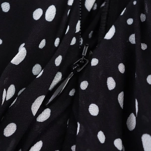 Detailed macro view of a black hidden zipper on white polka dot fabric dress