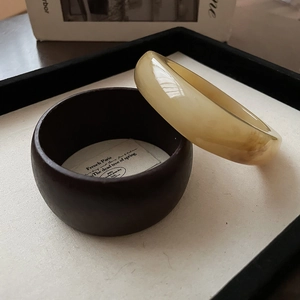 Artistic close-up of a chunky resin bangle on a dark wood stand with a retro vintage aesthetic