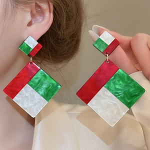 Macro detail of geometric acrylic drop earrings with marble texture and bold tricolor design