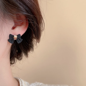 Gros plan de boucles d'oreilles nœud noir élégantes portées par un mannequin